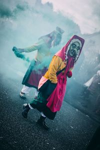 People wearing masks with distress flare on road during carnival