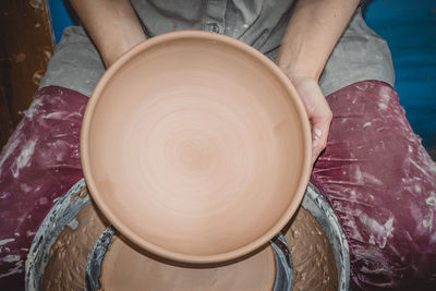 Master potter holds round clay plate in his hands. sculptor sculpts pots products from white clay. 