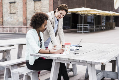 Two businesswomen working on terrace of a pavement cafe