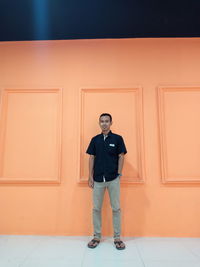 Full length portrait of young man standing against door