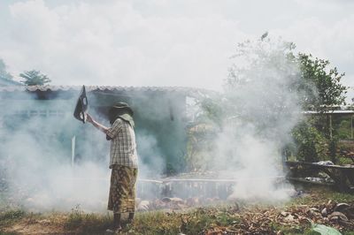 Man waving smoke while standing on land