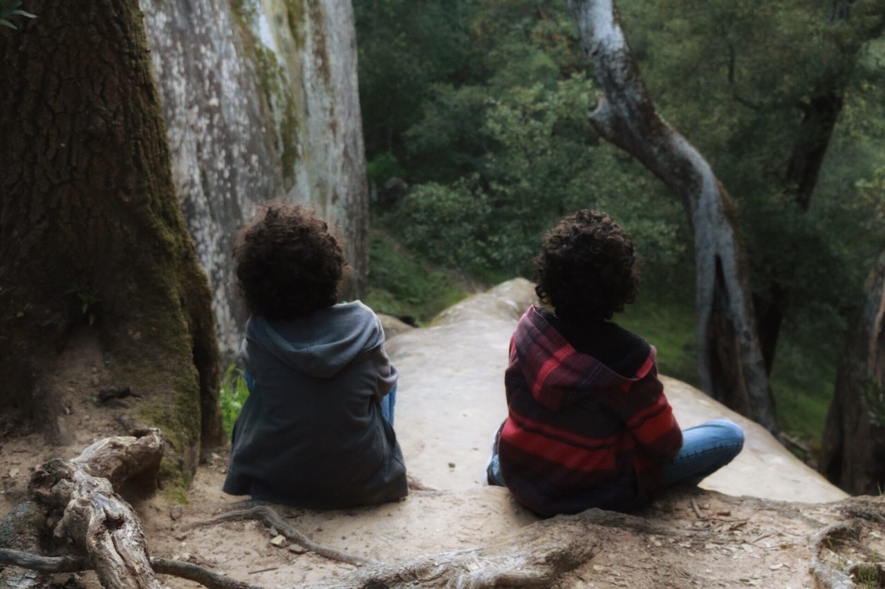 two people, real people, sitting, rear view, togetherness, childhood, tree, rock - object, leisure activity, casual clothing, day, family, outdoors, love, girls, nature, lifestyles, full length, boys, women, bonding, beauty in nature, friendship, young adult, people