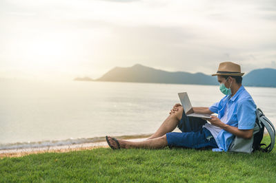 Side view of man sitting on field