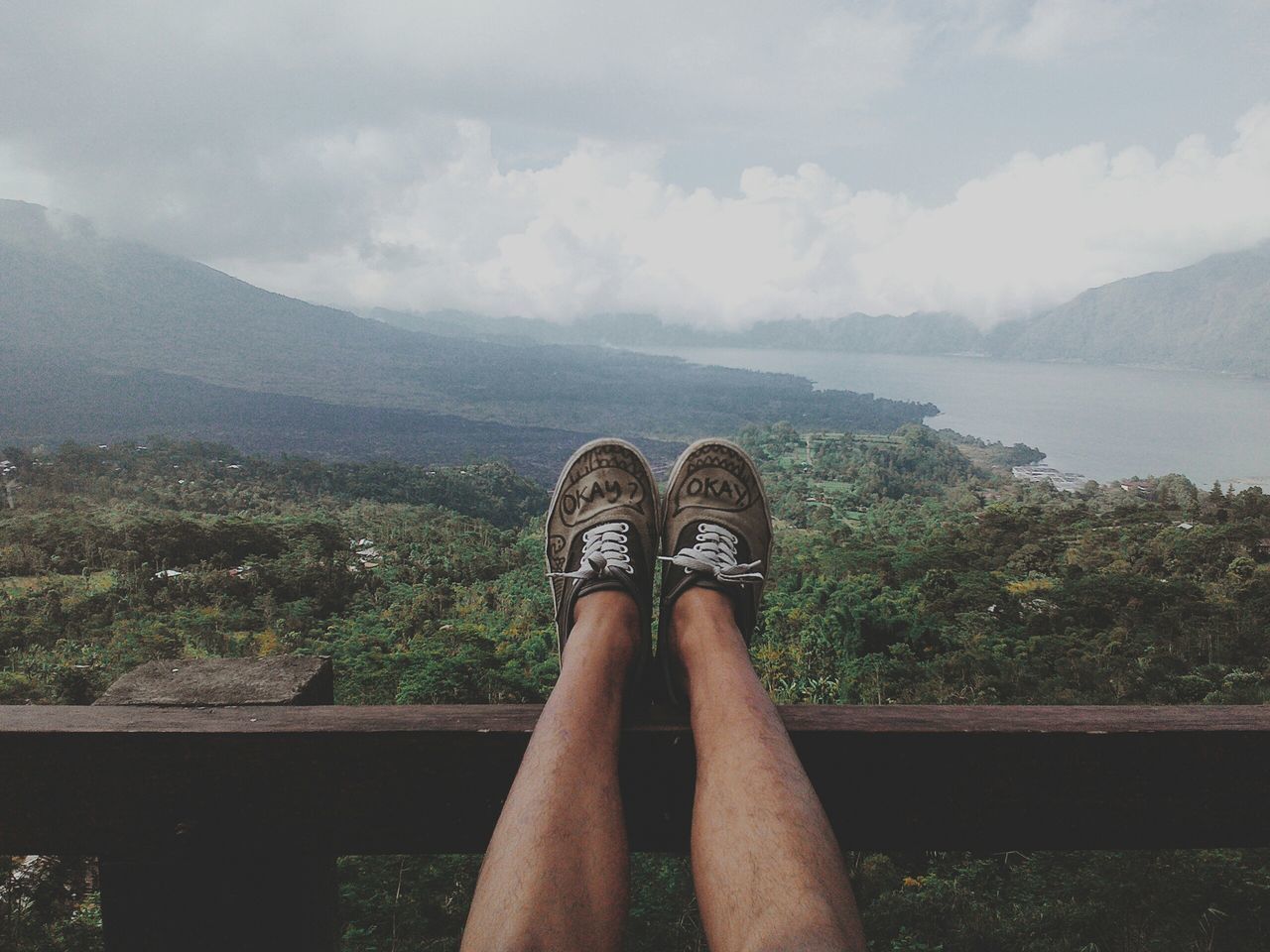 low section, person, personal perspective, mountain, shoe, sky, lifestyles, mountain range, water, lake, leisure activity, human foot, standing, cloud - sky, footwear, scenics, nature