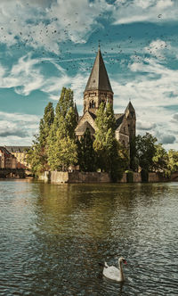 View of lake with buildings against cloudy sky