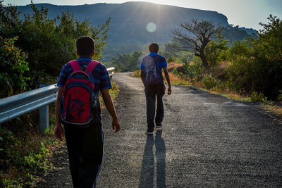 Rear view of men walking on road