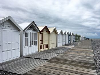 Wooden houses on beach by buildings against sky