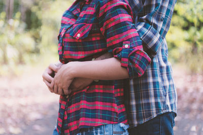 Midsection of couple embracing while standing outdoors