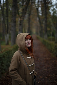 Portrait of young woman standing against trees