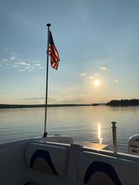 Flag on lake against sky during sunset