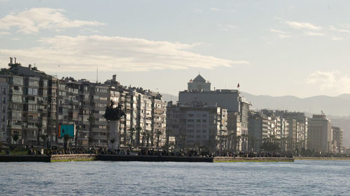 Sea by buildings against sky in city