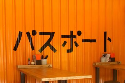 Information sign on table against orange wall