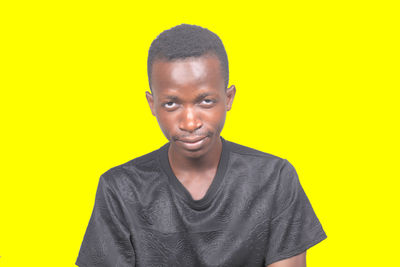 Portrait of young man standing against yellow background