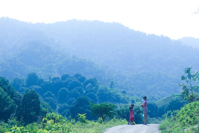 Siblings standing on mountain road