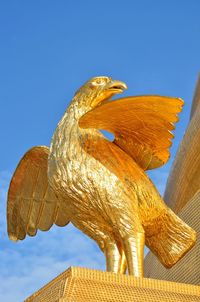 Low angle view of golden eagle statue at temple against sky