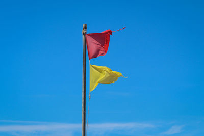 Low angle view of flag against blue sky