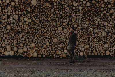 Man standing in front of stack of logs