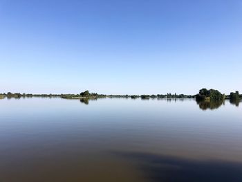 Scenic view of lake against clear blue sky