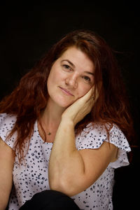 Portrait of smiling young woman against black background