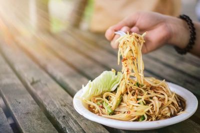 Midsection of person holding noodles on table