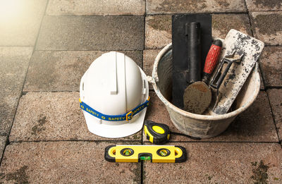 High angle view of white hardhat with work tools on floor