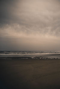 Scenic view of beach against sky at dusk