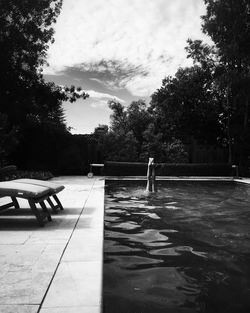 Wet table by trees against sky