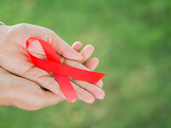 Cropped hand of woman holding aids awareness ribbon