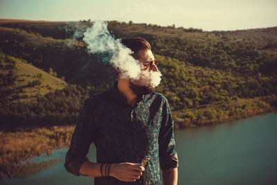 Man smoking while standing by lake