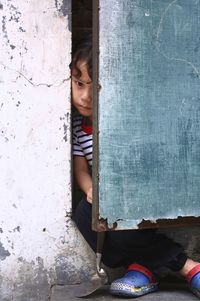 Mid adult woman sitting by entrance against wall