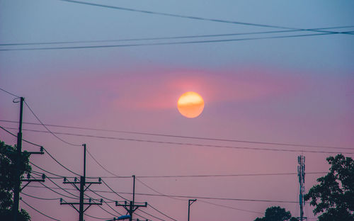 Low angle view of silhouette electricity pylon against sky during sunset