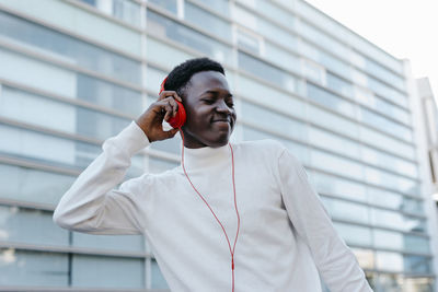 Smiling young man listening music through orange headphones