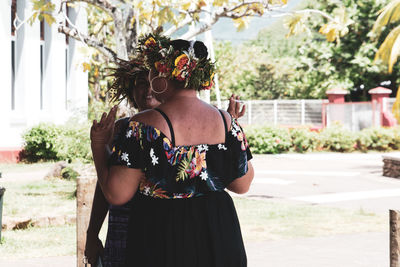 Rear view of woman standing by flowering plants