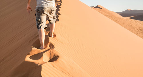 Low section of person on sand at desert