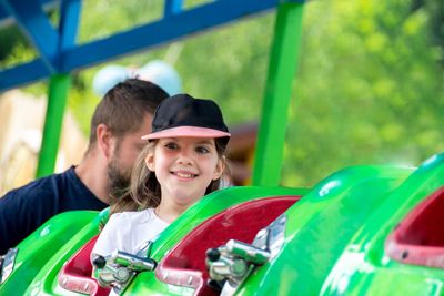 Two funny kid riding on ladybug on roundabout carousel in amusement park