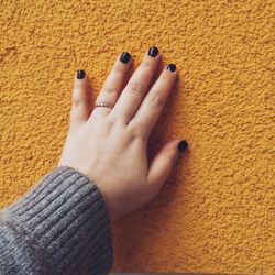 Close-up of woman hand on yellow wall