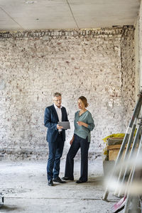 Architect working with colleague over digital tablet while standing at construction site