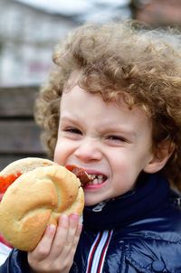 Close-up portrait of boy eating burger