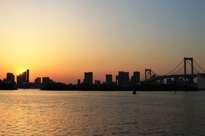 Silhouette rainbow bridge over tokyo bay against clear sky