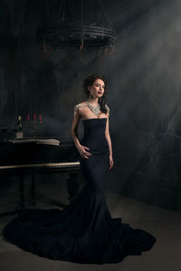 Beautiful woman in gown standing at home