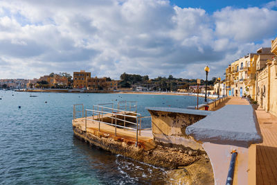 Scenic view of river by buildings against sky