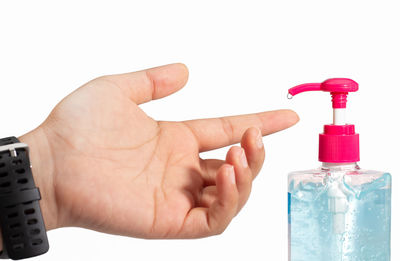 Close-up of hand holding bottle against white background