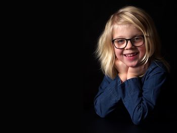 Portrait of smiling boy against black background