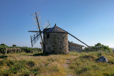 Traditional windmill on field against clear sky