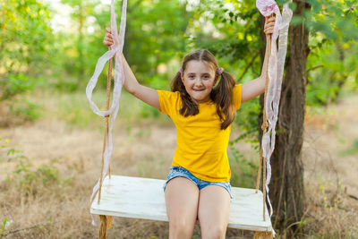 Portrait of young woman sitting on swing in park