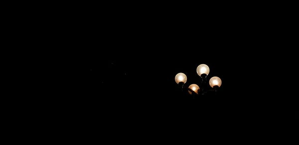 Low angle view of illuminated lamp against black background