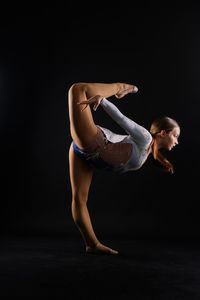Portrait of young woman exercising against black background