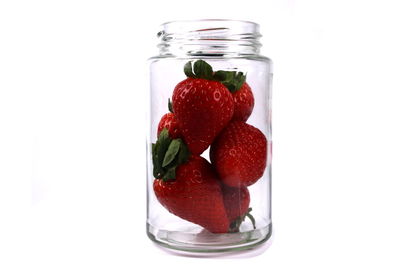 Close-up of strawberries in jar against white background