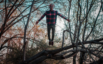 Low angle view of man standing by bare trees in forest