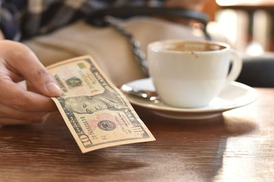 Close-up of hand holding coffee cup on table